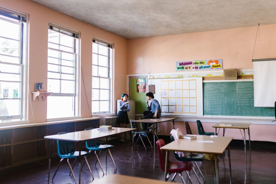 Two students having a conversation in a quiet classroom setting, surrounded by learning materials