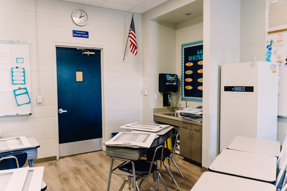 A spacious classroom with desks, blue door, and educational decor, conveying a learning environment
